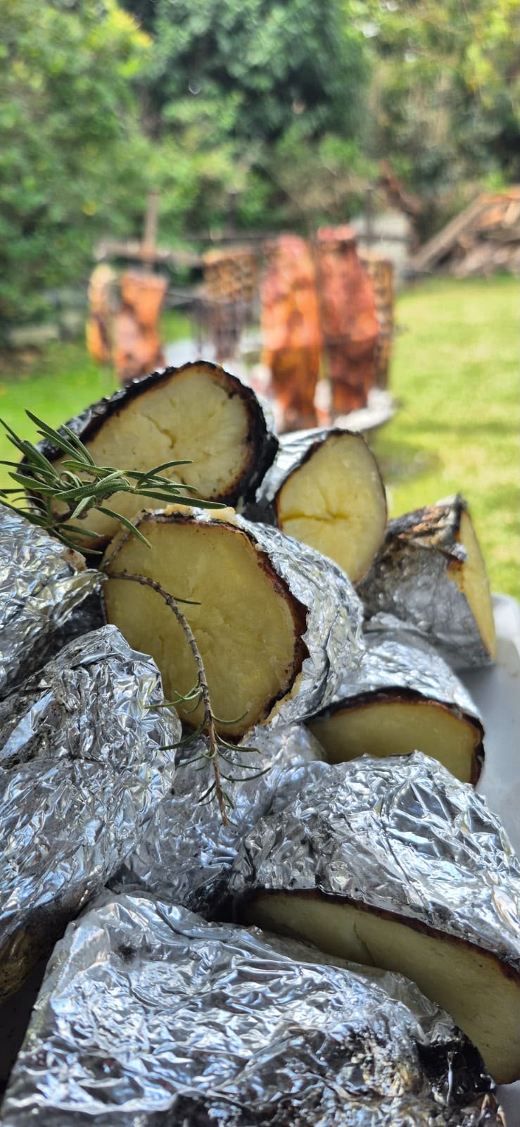 Batatas asadas al rescoldo con asadores a la cruz de fondo