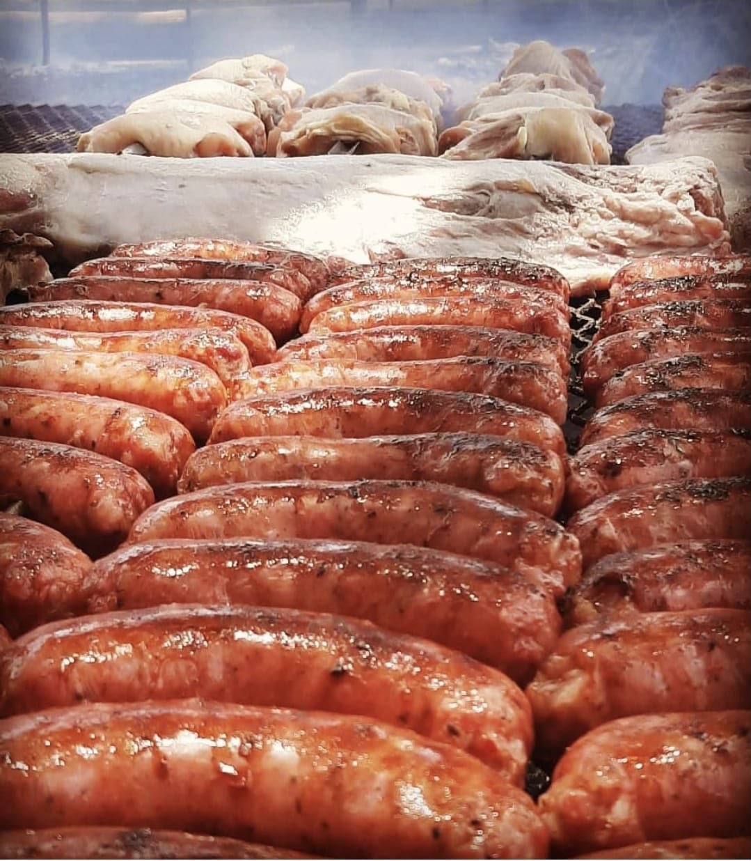 Chorizos y lechones asándose a la parrilla